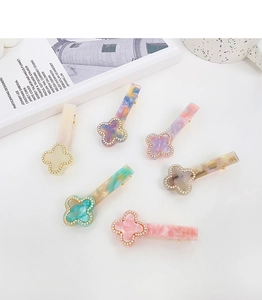 Detailed macro view of acetate clover hair clips with gold-tone accents and rhinestones