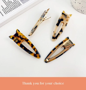 Close-up of tortoise shell cat-shaped hair clips with gold metal grips and sleek finish
