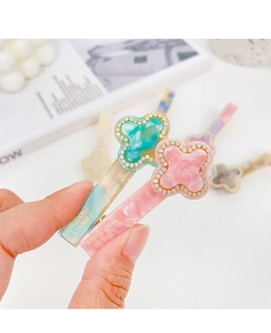 Close-up of handmade acetic hair clips in pink and blue with rhinestone clovers