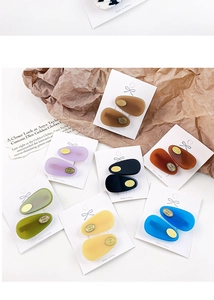 Macro shot of colorful acetate hair clips with golden brand plates on display card