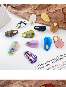 Flat lay of colorful marble acetate hair clips with golden duckbill clips on white base