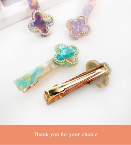 Detail view of colorful resin clover hair clips with sparkling rhinestones and gold clips