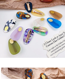 Macro detail of colorful acetate teardrop hair clips with gold metal duckbill clips