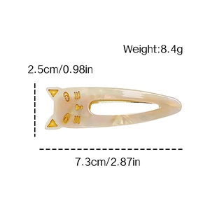 White acetate cat hair clip with gold details and dimensions 7.3cm x 2.5cm