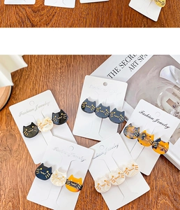 Detail of five cat-shaped hair clips in black, pearl white, and tortoiseshell on display card