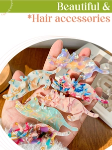 Detail of cat-shaped acetate hair clips with marble texture and golden engraved facial lines