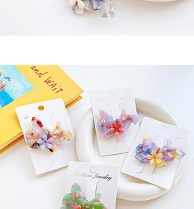 Détail de pinces à cheveux en acétate coloré avec fleur en strass sur une assiette