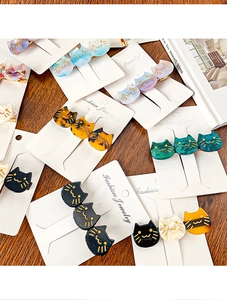 Detailed close-up of colorful acetate cat hair clips with golden accents on wood surface