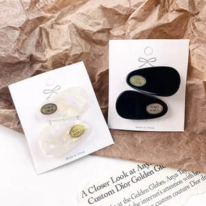 Elegant oval acetate hair clips in black and iridescent white on display cards
