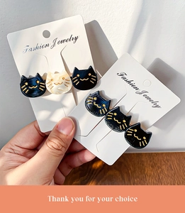 Detailed view of cat-shaped hair clips in black and white on a display card