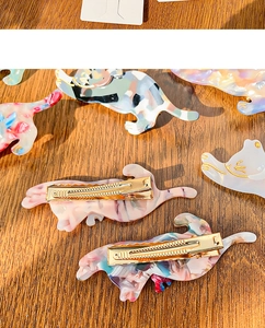 Detailed view of cat-shaped acetate hair clips with marble textures and metal grips