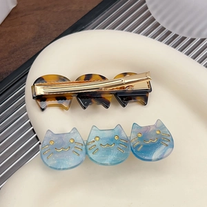 Chic cat shaped acrylic hair clips with golden accents on a ceramic display