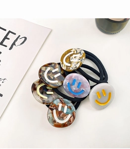 Detailed view of elastic hair bands set with textured acetate smile face charms