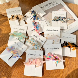 Cat-shaped acetate hair clips in various tortoiseshell colors on elegant wooden background