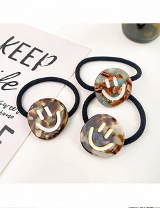 Three-piece acetate hair ties with tortoise shell charms and smiling face patterns