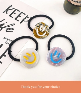 Detailed shot of three acetate hair ties featuring smiley face charms in various colors
