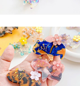 Dettaglio di fermagli per gatti in acetato blu, rosa e tartarugati con fiori di ciliegio