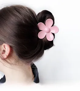 Gros plan détaillé d'une grande pince à cheveux fleur rose fixant un chignon élégant