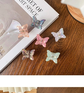 Vue détaillée de six mini pinces à cheveux papillon irisées sur un bureau en bois
