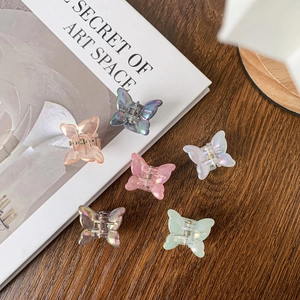 Lot de six barrettes papillon colorées avec finition nacrée sur un bureau en bois