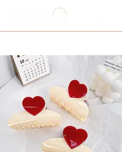 Vue détaillée des pinces à cheveux crème avec cœurs rouges 3D sur tissu doux