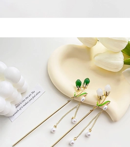 Detail view of Chinese style metal hairpins with enamel floral buds and golden tassels