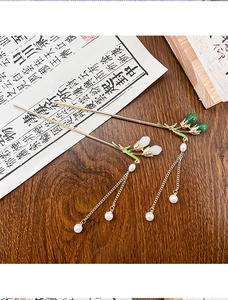 Close-up of gold Chinese hairpins with pearls and tassels on vintage calligraphy paper