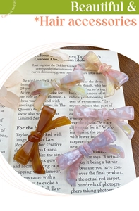 Detail of four handmade acetate bow hair clips in marble pink and amber finishes