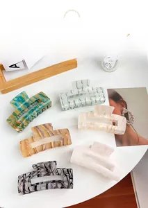 Flat lay of six marble textured acrylic hair claws in multiple colors on a white table