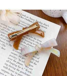 Detail of premium acetate bow hair clips in amber tortoiseshell and pearl white finishes