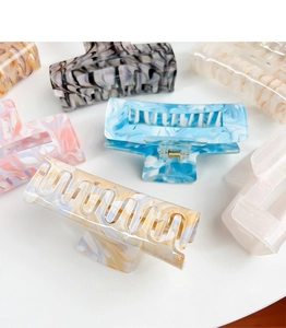 Detailed macro view showing marble pattern acrylic hair claws in multiple pastel colors