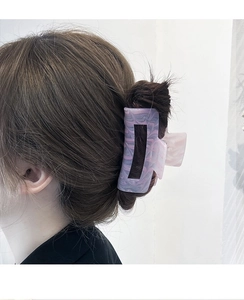 Detail of a large lilac marble acetate hair claw clip on a model's hair for styling