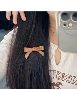 Close-up of amber bow hair clip with Handmade France gold lettering on acetate material