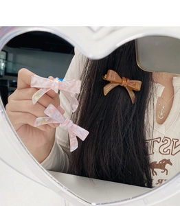 Detail of pink and brown acetate bow hair clips showing handmade gold lettering