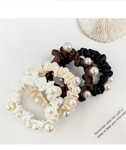 Detailed view of four satin scrunchies with large pearls in vintage French style