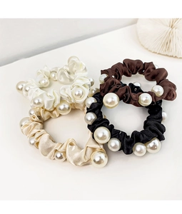 Detail of four satin scrunchies with large pearl accents in neutral elegant colors