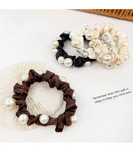 Detail of four satin scrunchies with white pearls in black, brown, and cream tones