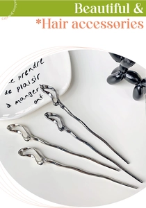 Macro detail of four silver irregular wavy hair sticks on a stylish white plate