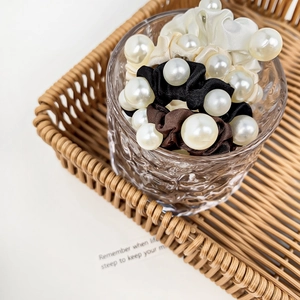Elegant satin scrunchies with large pearls in cream, black, and coffee in a glass