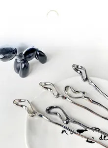 Close-up of modern liquid metal silver hairpins with irregular streamline design