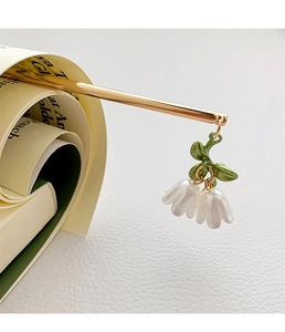 Detailed close-up of a Lily of the Valley hair stick with enamel flowers and gold stem