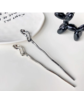 Detailed view of silver liquid metal hair sticks in a minimalist modern aesthetic