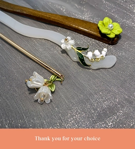 Close-up of vintage floral hair sticks with lily of the valley and gold metal details