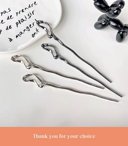 Minimalist silver wavy metal hair sticks in a stylish setting with a modern ceramic plate