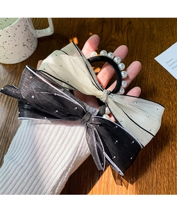 Detail of a large mesh bow hair tie with sparkling sequins and elastic pearl beads