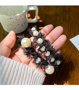 Macro view of vintage lace hair scrunchie with layered pearls and elegant black lace texture