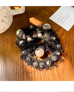 Close-up of black lace hair scrunchies with white pearls on a wooden surface