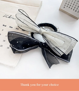 Detail of bow hair ties with organza ribbons and white pearls on a desktop