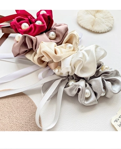 Détail de chouchous en satin avec perles et rubans en couleurs bordeaux, rose et or