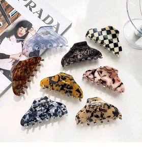 Flat lay of 8 large hair claws in marble and tortoiseshell patterns on white surface